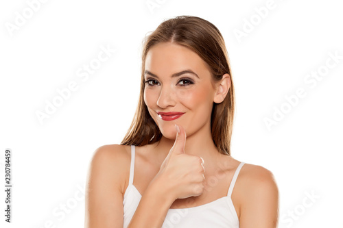Portrait of young beautiful woman with makeup on white backgeound and showing thumbs up