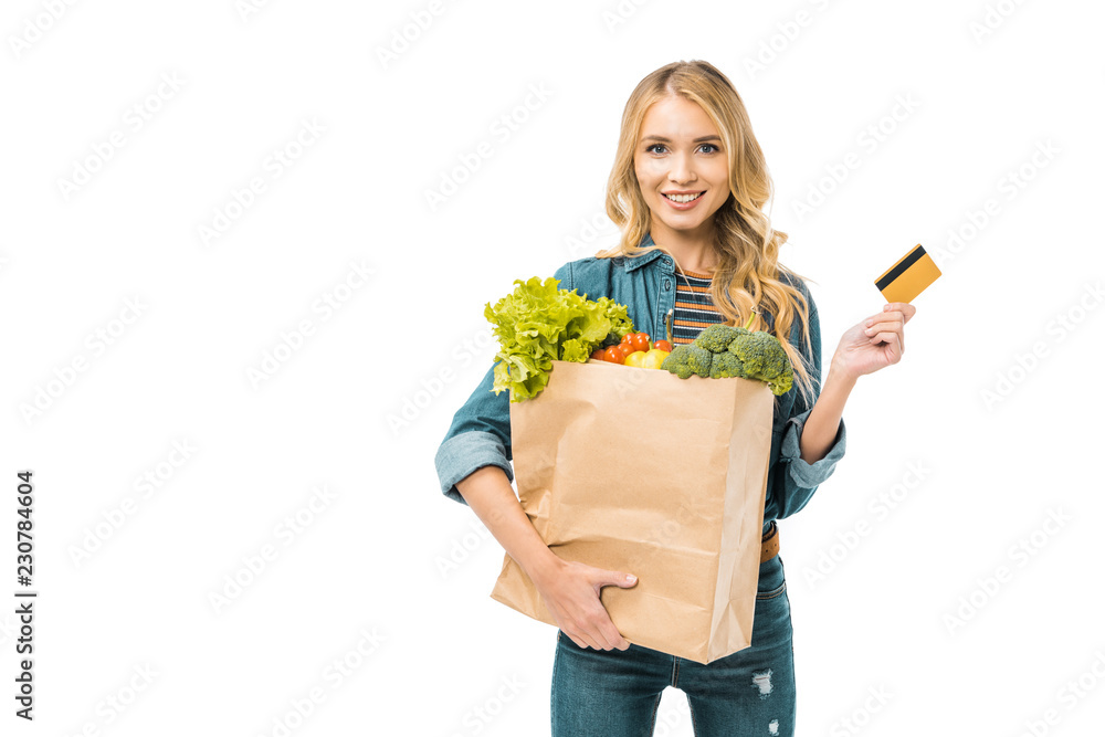 beautiful girl holding shopping bag with food and showing credit card isolated on white beautiful girl holding shopping bag with food and showing credit card isolated on white