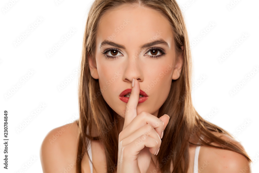 Beautiful girl with finger over her lips on white background Beautiful girl with finger over her lips on white background