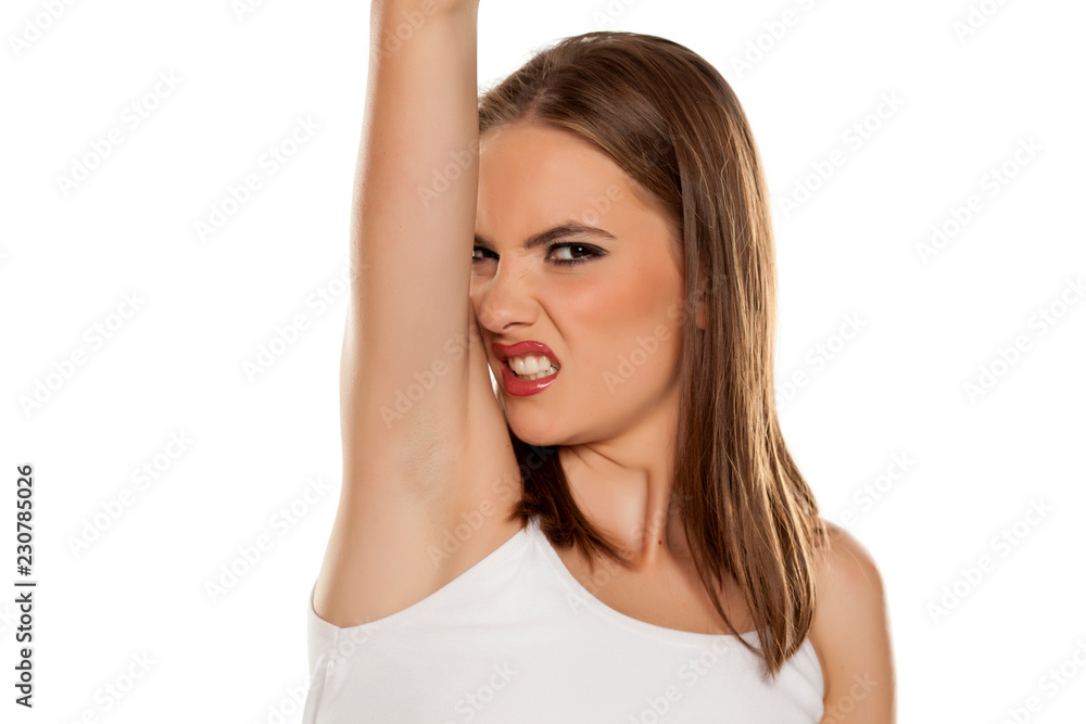 Beautiful girl smelling her armpit on white background