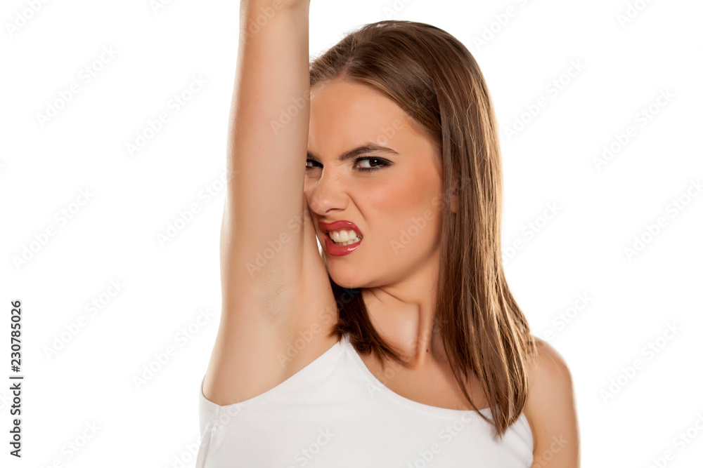 Beautiful girl smelling her armpit on white background Beautiful girl smelling her armpit on white background
