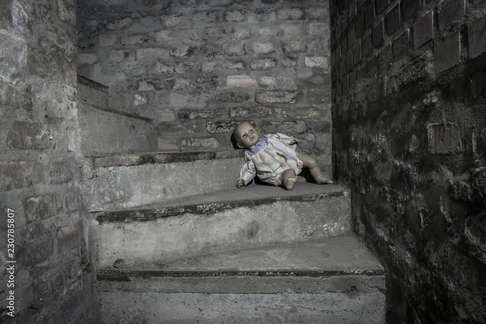 Scary demonic doll sitting on the steps in the basement Scary demonic doll sitting on the steps in the basement