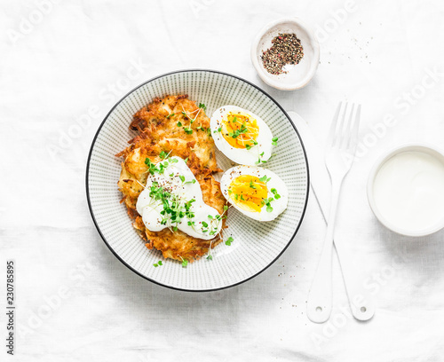 Potato latkes and boiled egg - healthy breakfast or snack on light background, top view