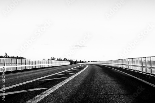 Empty highway in black and white over bridge.