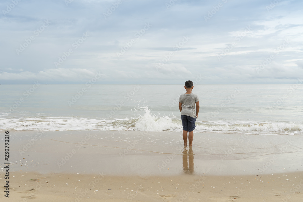 Asian little kid standing and looking at the sea in day time. leisure and people concept