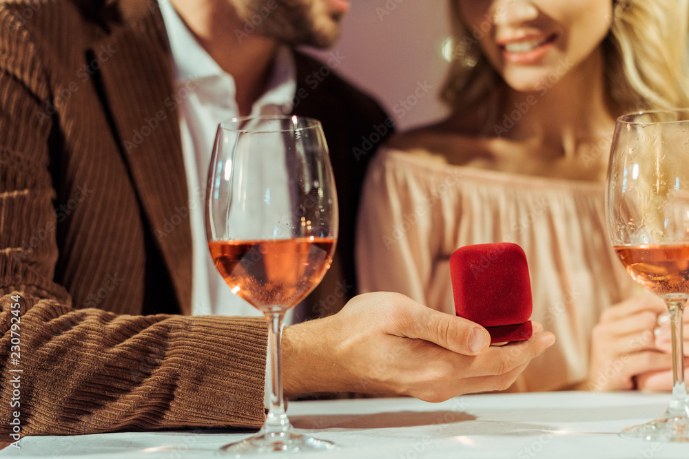 cropped image of man proposing to girlfriend during romantic dinner in restaurant cropped image of man proposing to girlfriend during romantic dinner in restaurant