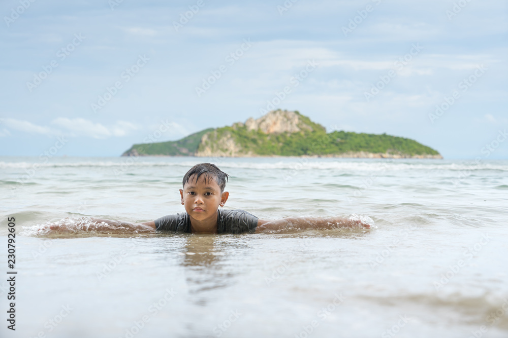 Asian boy enjoying in the sea near the beach at Ao Manao, Prachuap Khiri Khan, Thailand in the afternoon.