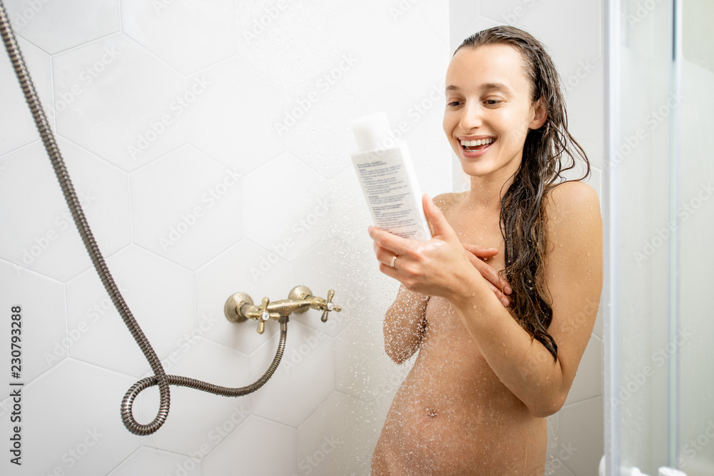 Naked woman with white bottle of shampoo or lotion in the shower cabin  taking a shower Stock Photo | Adobe Stock