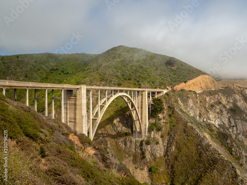 Big Sur California coast, Rocky creek bridge, beach, rocks, clouds, and surfing waves