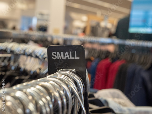 Small clothes section sign on steel hanging rack with hangers in department store