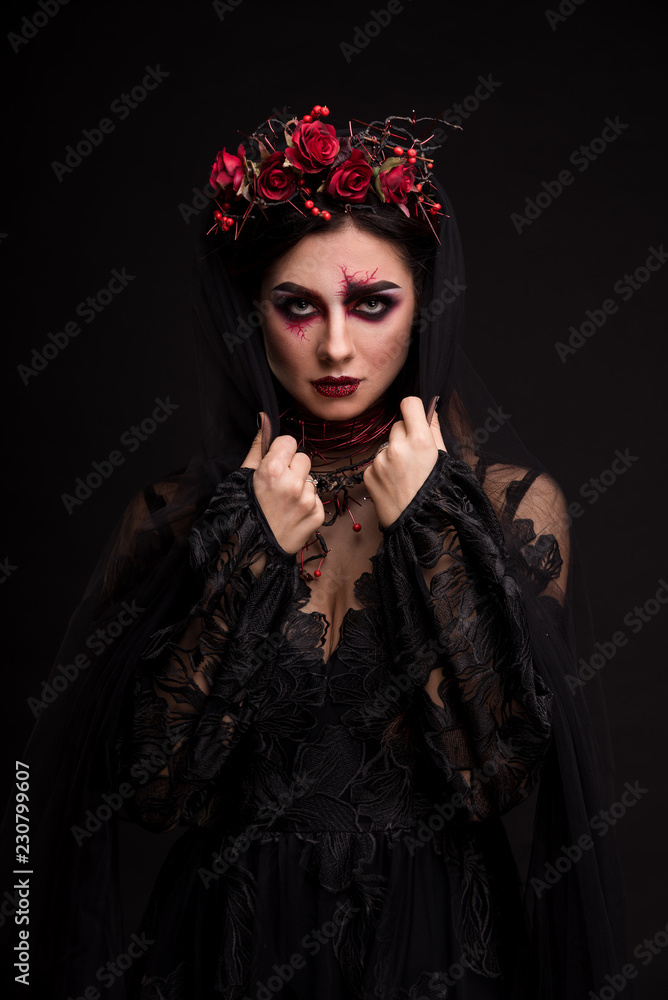 Portrait of a girl in the image for Halloween. Black Widow. Wreath of roses. Makeup for halloween. Keeps veil. Eyes like gimlets. Black background.