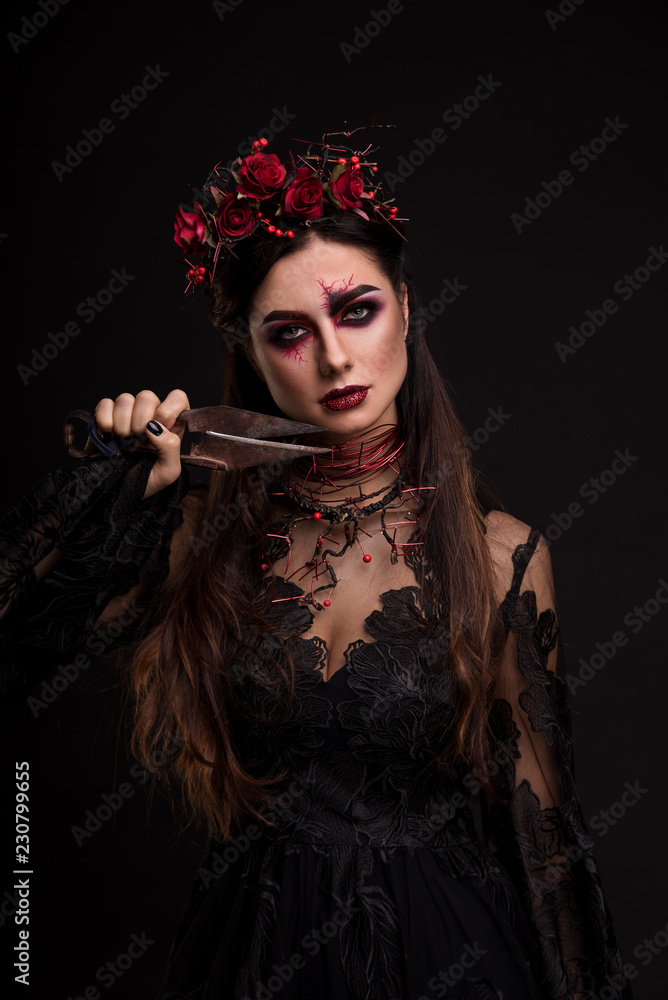 Portrait of a girl in the image for Halloween. Old scissors on the face. Black Widow. Wreath of roses. Makeup for halloween. Eyes like gimlets. Black background. Portrait of a girl in the image for Halloween. Old scissors on the face. Black Widow. Wreath of roses. Makeup for halloween. Eyes like gimlets. Black background.