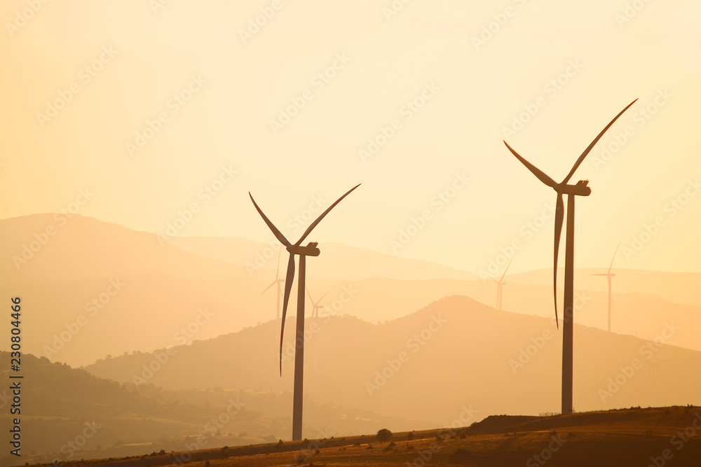 Obraz premium Wind power generators on the background of silhouettes of mountain peaks. Simplicity and minimal lines. Beautiful landscape of the power of nature. 