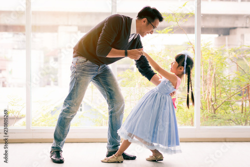 Cute little girl is dancing with her daddy. Having fun at home together concept