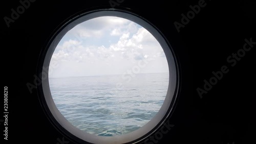 peaceful view through porthole of a sailing vessel in calm seas at sunset