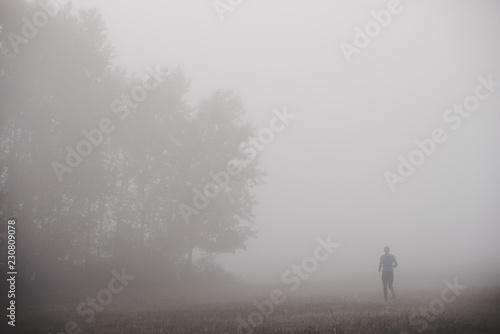 Runner silhouette in blue autumn morning mist