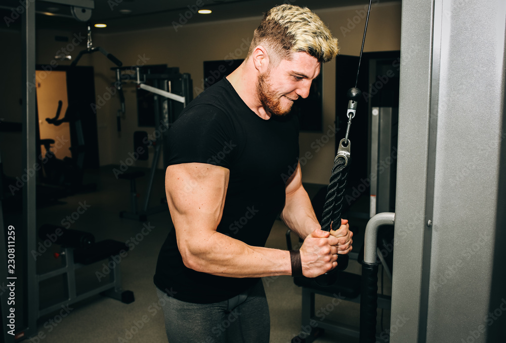 Blonde man is training in the gym with weights. Handsome guy is doing exercises for good muscles. Fitness personal trainer is at work. Sport motivation healthy lifestyle. Fit bodybuilder. Blonde man is training in the gym with weights. Handsome guy is doing exercises for good muscles. Fitness personal trainer is at work. Sport motivation healthy lifestyle. Fit bodybuilder.