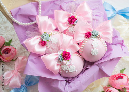 winter vacation. New Year's toys made by hand. a set of pink Christmas balls with a bow of satin ribbon, lace, flowers lies in a box with purple paper.