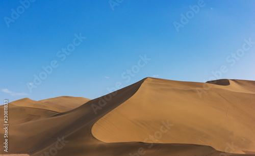 Desert sand dunes with blue sky background. Beautiful curves of deserts