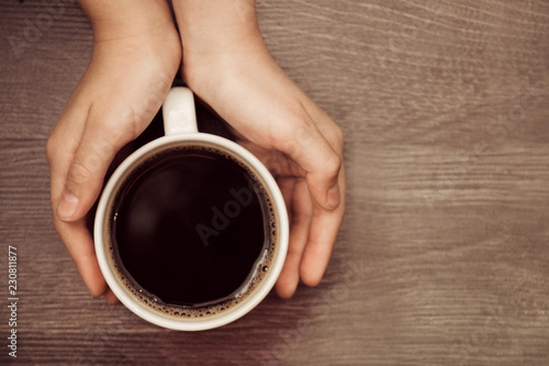 a cup of coffee in your hands on wooden background