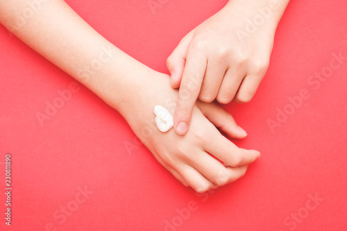the woman s hand smeared her hand with cosmetic cream lotion with a copy of space on a red background of minimalism. The concept of women s pattern blog