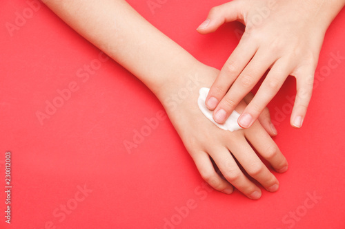 the woman s hand smeared her hand with cosmetic cream lotion with a copy of space on a red background of minimalism. The concept of women s pattern blog