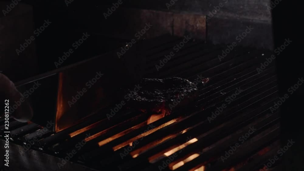Chef making burger. Beef or pork meat barbecue burgers for hamburger prepared grilled on bbq fire flame grill. Close-up shot of chef's hands turn the chop on the grill Chef making burger. Beef or pork meat barbecue burgers for hamburger prepared grilled on bbq fire flame grill. Close-up shot of chef's hands turn the chop on the grill