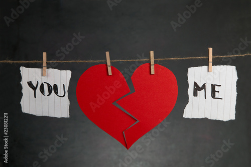 St Valentine's Day background. Red broken heart hanging on rope on black background with copy space.
