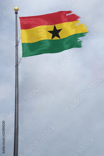 Worn and tattered Ghana flag blowing in the wind on a cloudy day