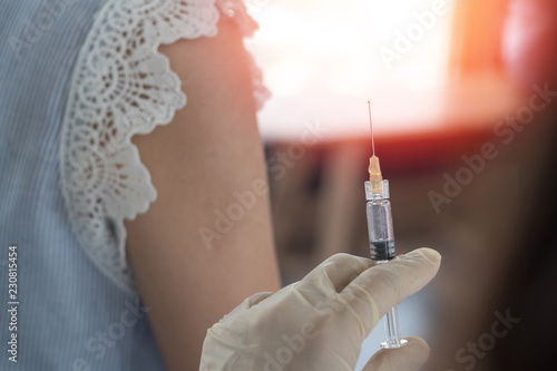 World immunization week and International HPV awareness day concept. Woman having vaccination for influenza or flu shot or HPV prevention with syringe by nurse or medical officer.