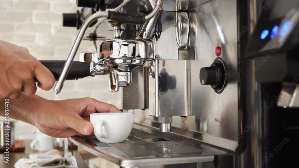 Barista brewing fresh coffee into the cup with machine in cafe - dolly shot