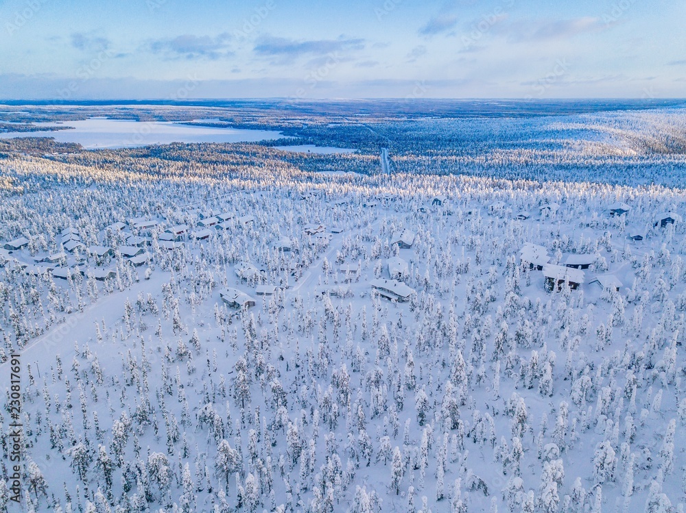 Obraz premium Aerial view of winter forest with frosty trees, rural road and village in Finland