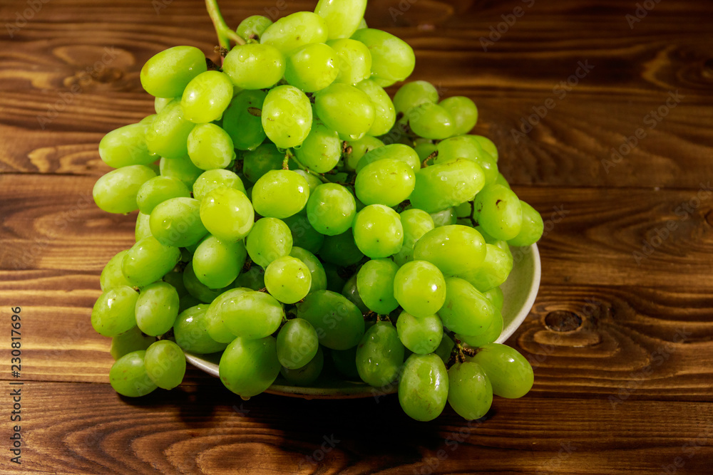 Tasty fresh white grape in a plate on wooden table