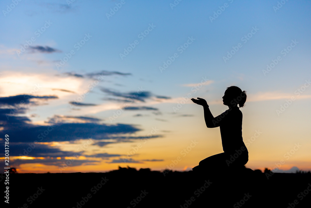 Silhouette woman praying over beautiful sky background