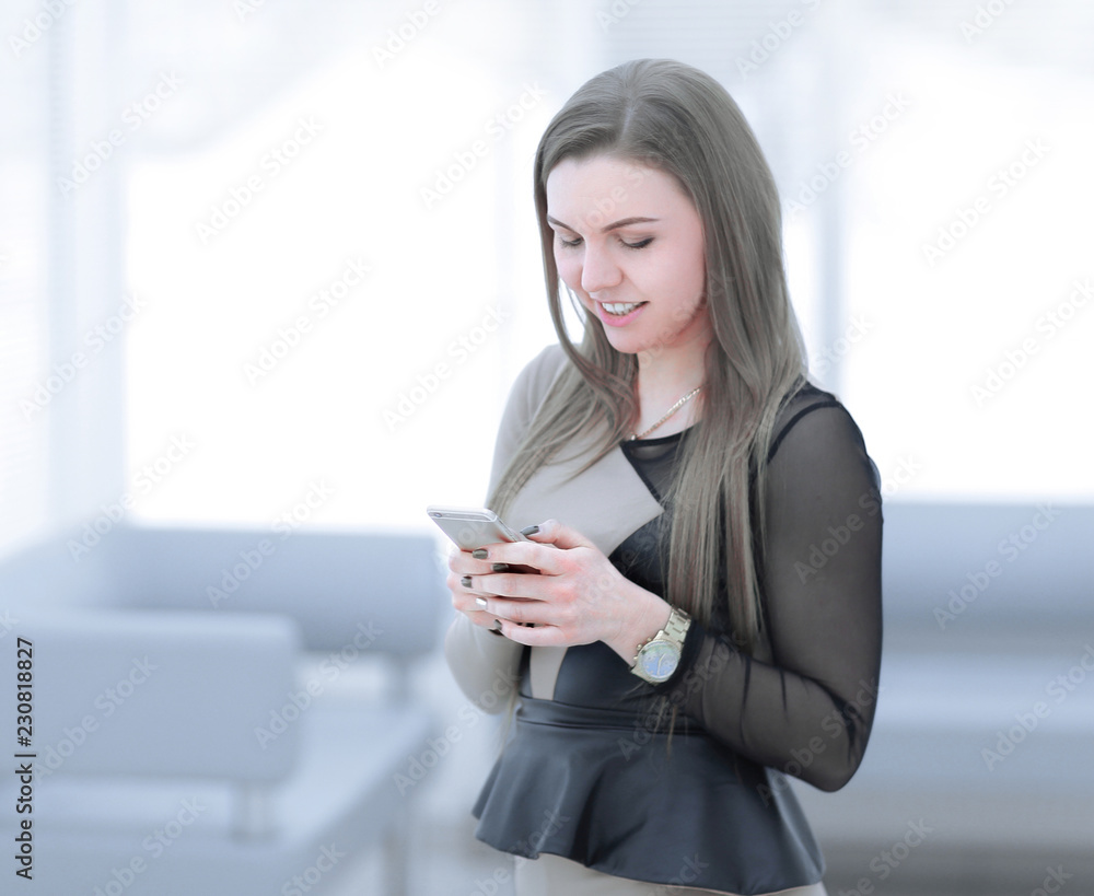 young woman typing text message on smartphone,while standing in the office young woman typing text message on smartphone,while standing in the office
