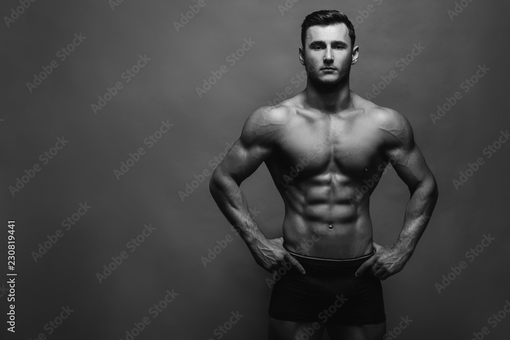 Naklejka premium Bodybuilding. Strong man posing on background. Athletic young boy showing muscles.
