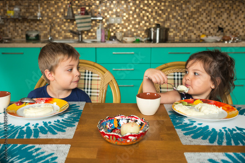 Portrait of boy and his little sister eating breakfast in the kitchen photo