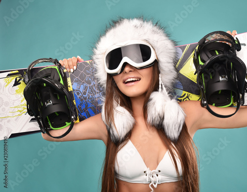 sexy sportswoman in white swimsuit holding snowboard on shoulders isolated on blue