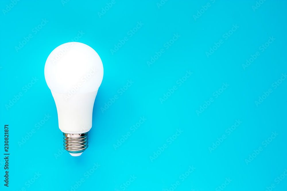 Glowing LED light bulb on blue background for energy savings concept Glowing LED light bulb on blue background for energy savings concept