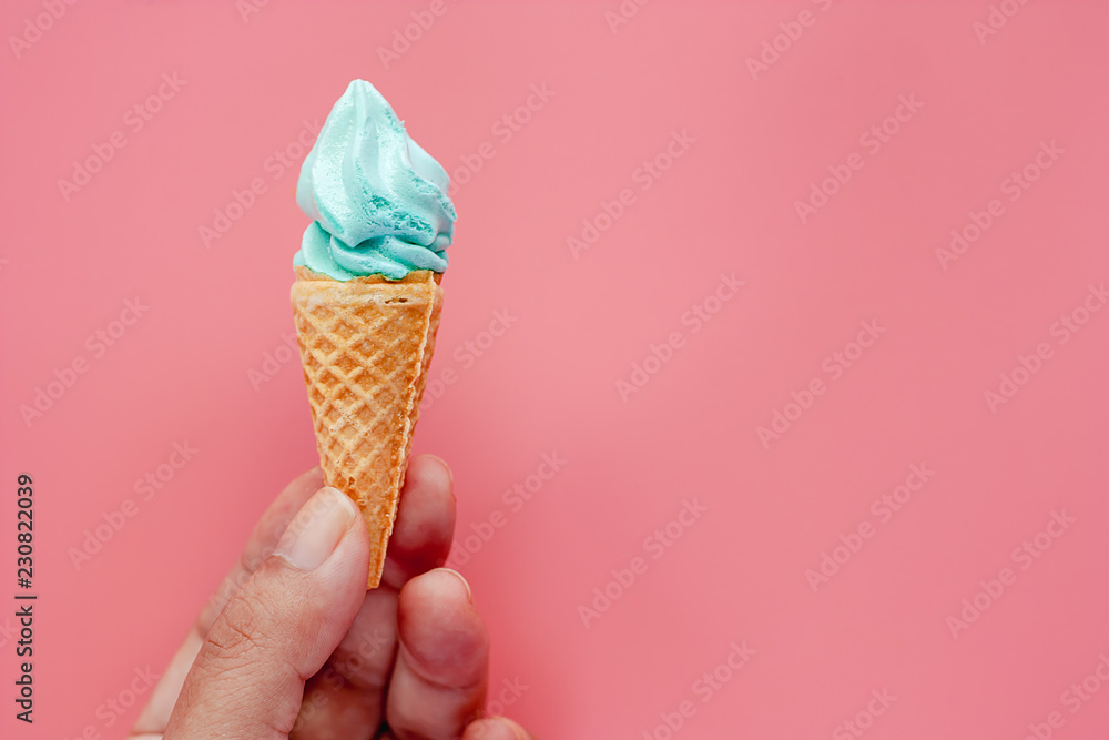 Hand holding ice cream cone on pink background for sweet and refreshing dessert concept Hand holding ice cream cone on pink background for sweet and refreshing dessert concept