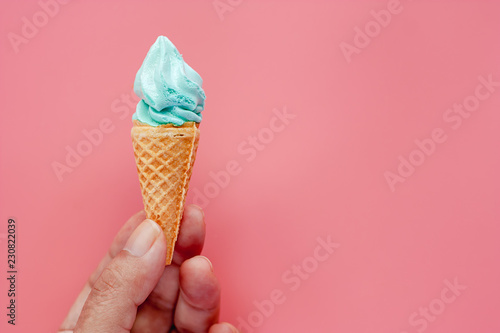 Hand holding ice cream cone on pink background for sweet and refreshing dessert concept