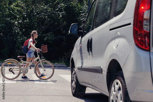 Teenage girl with backpack and bike on pedestrian crossing
