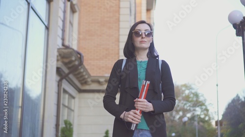 Canvas-taulu portrait of a blind girl in glasses with a cane on a city street