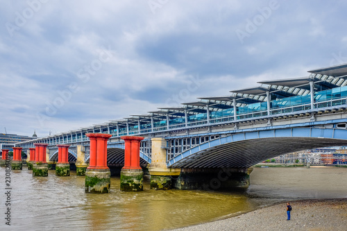 London, U.K, Aug 2018, man standing on the Thames riverbank at low tide by the Blackfriars Railway Bridge