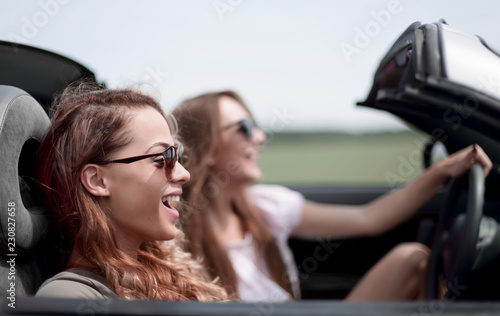 two fashionable girls travel in a convertible car. © ASDF