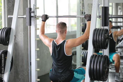 Fit young man in sportswear focused on lifting a dumbbell or boxing during an exercise class in a gym
