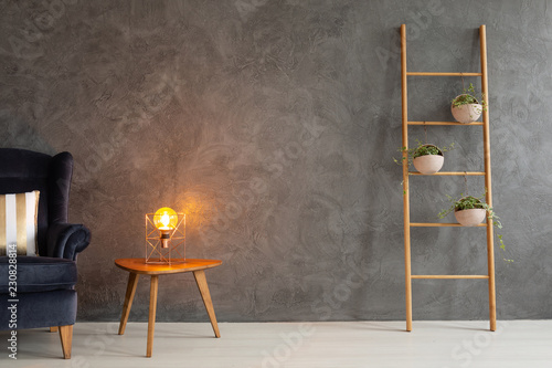 Modern lamp on elegant wooden table in simple and trendy interior with dark empty wall, real photo with copy space