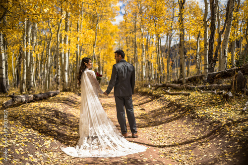 Obraz na płótnie Wedding/engagement photography - Beautiful Asian/Vietnamese bride in wedding dress with caucasian groom in the beautiful fall/autumn yellow leaves. Colorado Rocky Mountains. Aspen, Colorado. USA w salonie