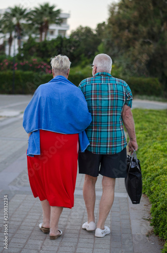 An elderly couple on vacation in bright clothes.
