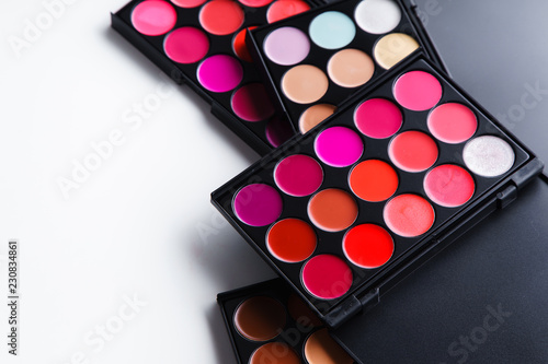 Various lipstick and eye concealer palettes with lots of colors isolated on white background. Make-up artist kit concept